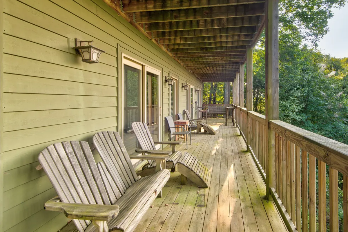 A cozy deck area with wooden and Adirondack chairs overlooks the surrounding greenery. The space is perfect for lounging, reading, and enjoying the peaceful sights and sounds of nature, enhancing the sense of being immersed in the outdoors.